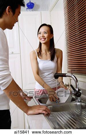 Couple in kitchen, woman washing dishes, smiling at man View Large Photo Image Stock Image - Couple in kitchen, woman washing dishes, smiling at man. Fotosearch