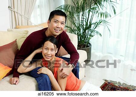 Couple in living room, smiling at camera, portrait View Large Photo Image Stock Photography - Couple in living room, smiling at camera, portrait. Fotosearch