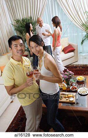 Couple in living room with wine glasses, smiling at camera View Large Photo Image Stock Photo - Couple in living room with wine glasses, smiling at camera. Fotosearch