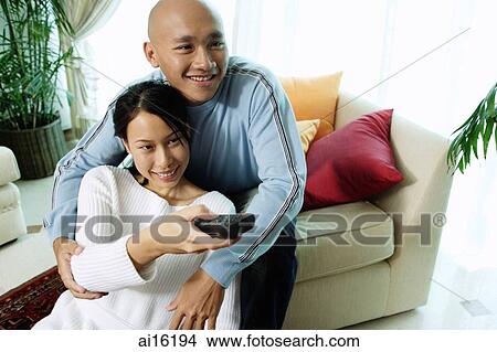 Couple in living room, woman holding remote control View Large Photo Image Picture - Couple in living room, woman holding remote control. Fotosearch