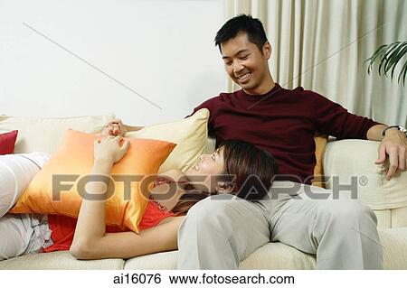 Couple in living room, woman lying on mans lap View Large Photo Image Stock Photograph - Couple in living room, woman lying on mans lap. Fotosearch