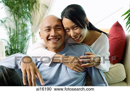 Couple in living room, woman with arm around man, smiling at camera, portrait View Large Photo Image Stock Image - Couple in living room, woman with arm around man, smiling at camera, portrait. Fotosearch