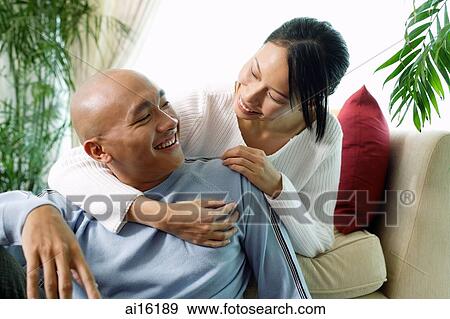 Couple in living room, woman with arm around man View Large Photo Image Stock Photo - Couple in living room, woman with arm around man. Fotosearch