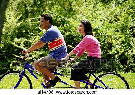 Couple in park, riding tandem bicycle View Large Photo Image Stock Photo - Couple in park, riding tandem bicycle. Fotosearch