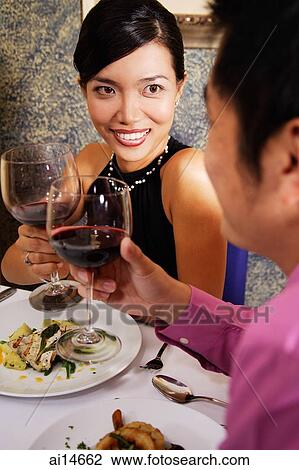 Couple in restaurant holding wine glasses for a toast View Large Photo Image Stock Image - Couple in restaurant holding wine glasses for a toast. Fotosearch
