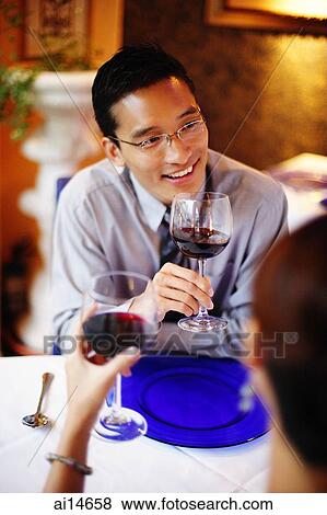 Couple in restaurant, holding wine glasses View Large Photo Image Stock Photo - Couple in restaurant, holding wine glasses. Fotosearch