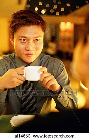 Couple in restaurant, man holding cup View Large Photo Image Stock Image - Couple in restaurant, man holding cup. Fotosearch