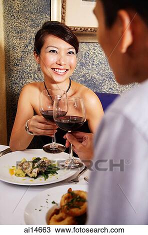 Couple in restaurant toasting with wine glasses View Large Photo Image Stock Image - Couple in restaurant toasting with wine glasses. Fotosearch