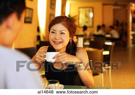 Couple in restaurant, woman with coffee cup, facing man View Large Photo Image Stock Photo - Couple in restaurant, woman with coffee cup, facing man. Fotosearch