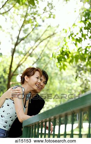 Stock Image - Couple leaning on railing, outdoor location. Fotosearch