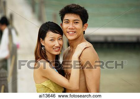 Couple looking at camera, jetty in the background View Large Photo Image Stock Photograph - Couple looking at camera, jetty in the background. Fotosearch