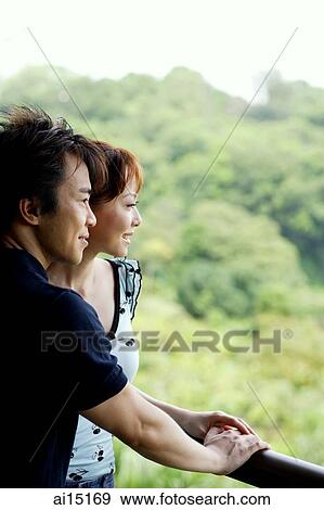 Stock Photo - Couple looking away, leaning on railing. Fotosearch