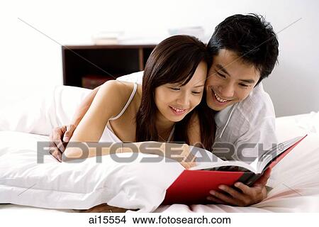 Couple lying on bed, reading book View Large Photo Image Picture - Couple lying on bed, reading book. Fotosearch