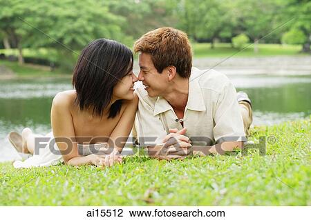 Couple lying on grass, face to face View Large Photo Image Stock Image - Couple lying on grass, face to face. Fotosearch
