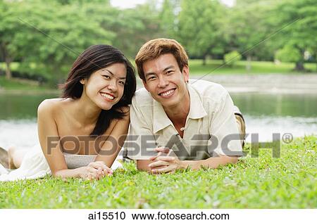 Couple lying on grass, smiling at camera View Large Photo Image Stock Image - Couple lying on grass, smiling at camera. Fotosearch