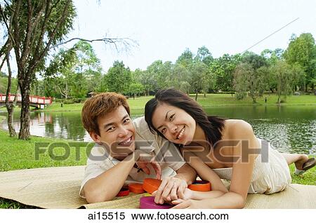 Couple lying on mat in park, looking at camera View Large Photo Image Stock Photography - Couple lying on mat in park, looking at camera. Fotosearch