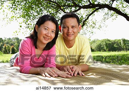 Couple lying on picnic mat, looking at camera, portrait View Large Photo Image Stock Photo - Couple lying on picnic mat, looking at camera, portrait. Fotosearch