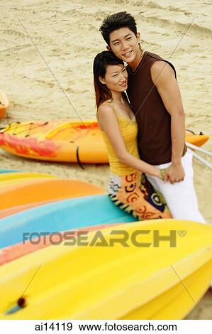 Stock Photo - Couple on beach, holding hands, looking away. Fotosearch