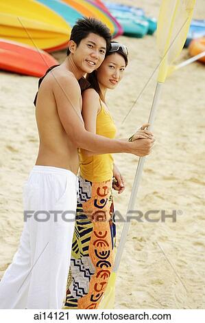Couple on beach holding kayak paddle, looking at camera View Large Photo Image Stock Image - Couple on beach holding kayak paddle, looking at camera. Fotosearch