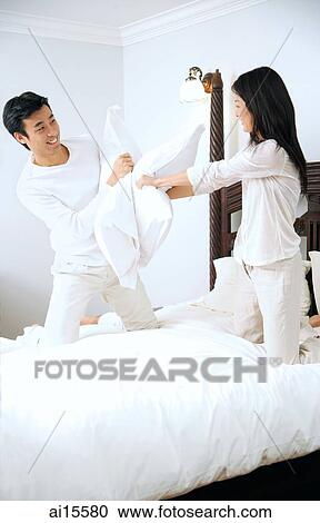 Couple on bed, having a pillow fight View Large Photo Image Stock Image - Couple on bed, having a pillow fight. Fotosearch