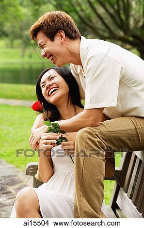 Couple on park bench, woman holding a rose, smiling View Large Photo Image Picture - Couple on park bench, woman holding a rose, smiling. Fotosearch