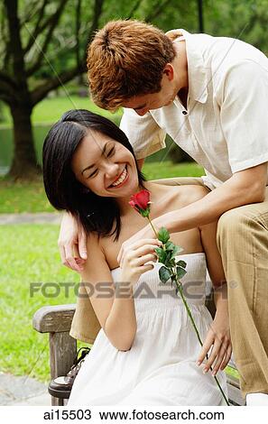 Couple on park bench, woman holding a rose View Large Photo Image Stock Image - Couple on park bench, woman holding a rose. Fotosearch