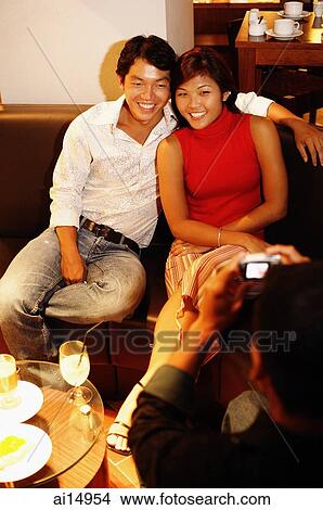 Couple on sofa, looking at camera View Large Photo Image Picture - Couple on sofa, looking at camera. Fotosearch