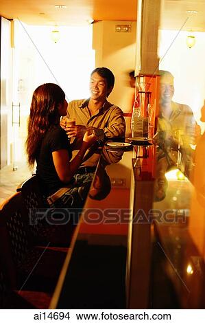 Couple sitting at bar counter, talking View Large Photo Image Picture - Couple sitting at bar counter, talking. Fotosearch
