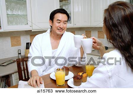 Couple sitting in kitchen, having breakfast View Large Photo Image Stock Image - Couple sitting in kitchen, having breakfast. Fotosearch