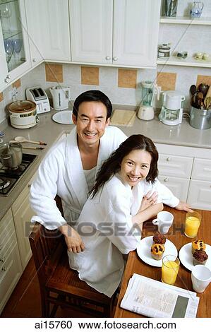 Couple sitting in kitchen, smiling at camera, high angle view View Large Photo Image Stock Image - Couple sitting in kitchen, smiling at camera, high angle view. Fotosearch