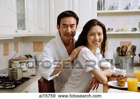 Couple sitting in kitchen, smiling at camera View Large Photo Image Stock Photo - Couple sitting in kitchen, smiling at camera. Fotosearch