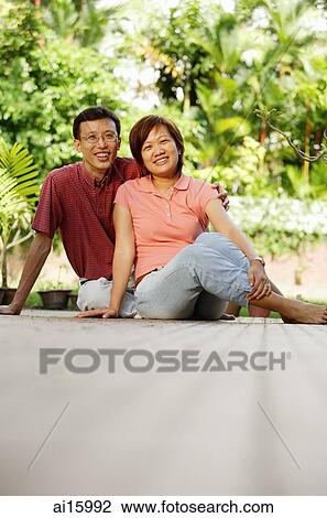 Couple sitting on floor, side by side, looking at camera View Large Photo Image Stock Image - Couple sitting on floor, side by side, looking at camera. Fotosearch