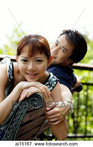 Couple sitting on park bench, looking at camera View Large Photo Image Stock Photo - Couple sitting on park bench, looking at camera. Fotosearch