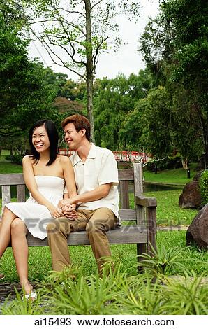 Couple sitting on park bench, woman laughing View Large Photo Image Stock Image - Couple sitting on park bench, woman laughing. Fotosearch