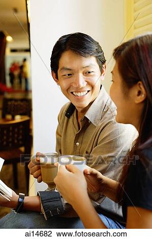 Couple sitting side by side, holding coffee cups View Large Photo Image Stock Image - Couple sitting side by side, holding coffee cups. Fotosearch