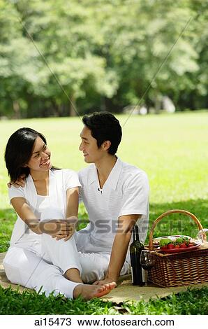 Couple sitting with picnic basket, smiling at each other View Large Photo Image Stock Image - Couple sitting with picnic basket, smiling at each other. Fotosearch