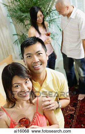 Stock Photo - Couple smiling at camera, people in the background. Fotosearch
