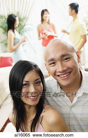 Couple smiling at camera, people in the background View Large Photo Image Stock Photography - Couple smiling at camera, people in the background. Fotosearch
