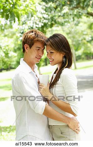 Stock Image - Couple standing face to face, embracing. Fotosearch
