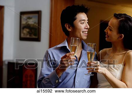 Couple standing face to face, holding champagne glasses View Large Photo Image Stock Image - Couple standing face to face, holding champagne glasses. Fotosearch