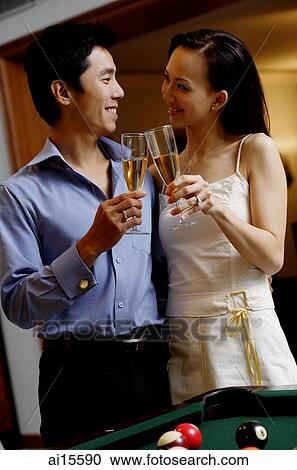 Stock Image - Couple standing side by side, toasting with champagne glasses. Fotosearch