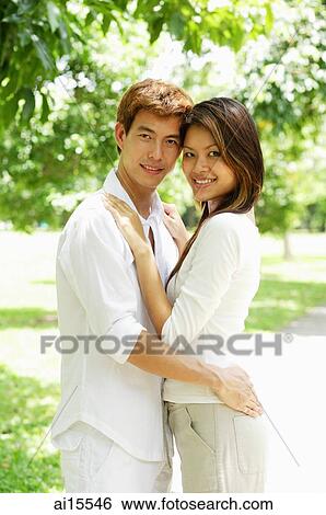 Couple standing together, embracing, looking at camera View Large Photo Image Stock Photograph - Couple standing together, embracing, looking at camera. Fotosearch