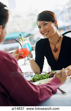 Stock Photo - Couple toasting with drinks over lunch. Fotosearch