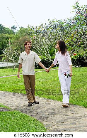 Stock Photo - Couple walking hand in hand in park. Fotosearch