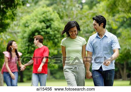 Couple walking, holding hands, people in the background View Large Photo Image Stock Photograph - Couple walking, holding hands, people in the background. Fotosearch