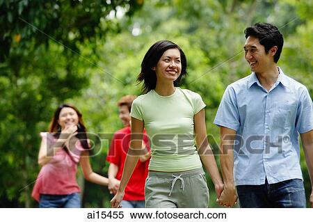 Couple walking, holding hands, people in the background View Large Photo Image Stock Photography - Couple walking, holding hands, people in the background. Fotosearch