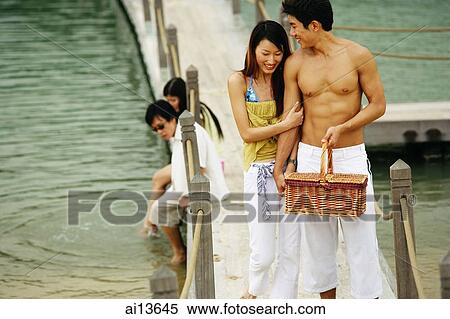 Couple walking on jetty, man carrying picnic basket, people in the background View Large Photo Image Stock Photography - Couple walking on jetty, man carrying picnic basket, people in the background. Fotosearch