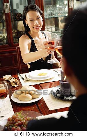 Couple with wine glasses, toasting across dining table View Large Photo Image Stock Image - Couple with wine glasses, toasting across dining table. Fotosearch