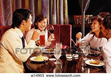 Stock Image - Couples at restaurant, eating. Fotosearch