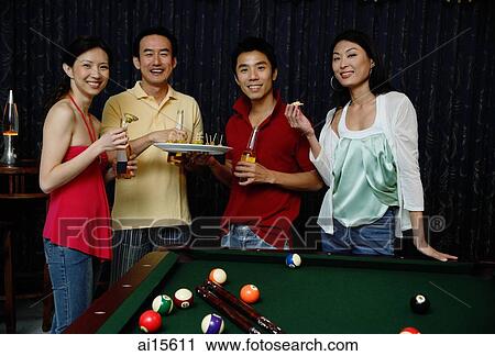Stock Image - Couples eating appetizers, smiling at camera. Fotosearch